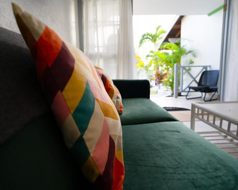 Sofá verde con cojines coloridos en la sala de estar del Sunset Lane Apartment Hotel con terraza y jardín