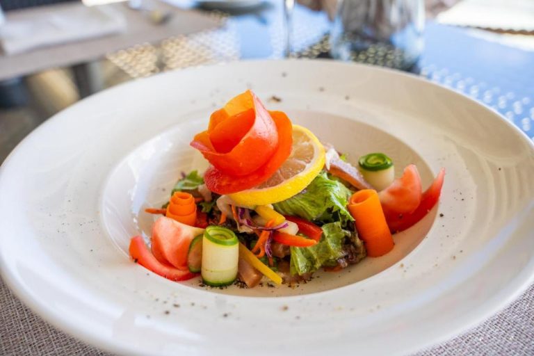 Ensalada fresca con verduras y frutas tropicales presentada en el restaurante de Le Nautique Waterfront Hotel La Digue