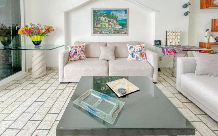 Sala de estar luminosa con sofá blanco y mesa de cristal en Playa Bonita Beso del Sol 101