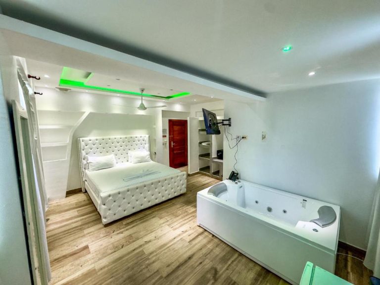 Suite de lujo con jacuzzi y cama tapizada blanca en Hotel Gran Real Punta Cana