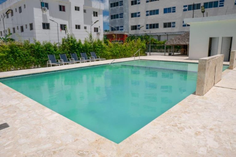 Piscina exterior de aguas turquesas con tumbonas y zona de descanso en Hotel Gran Real Punta Cana