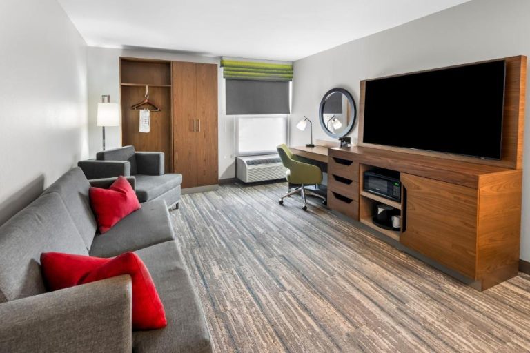 Suite con sofá gris, televisor de pantalla grande y zona de escritorio en Hampton Inn Indianapolis Castleton