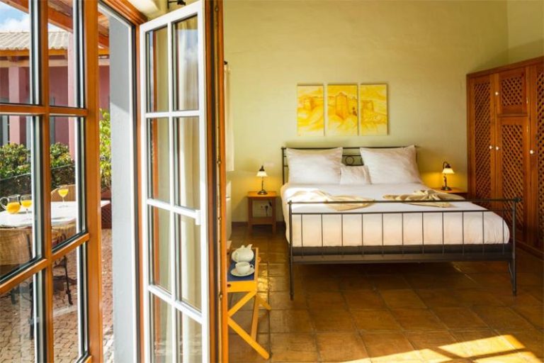 Habitación doble con cama de hierro forjado y terraza exterior soleada en el Hotel Atrio