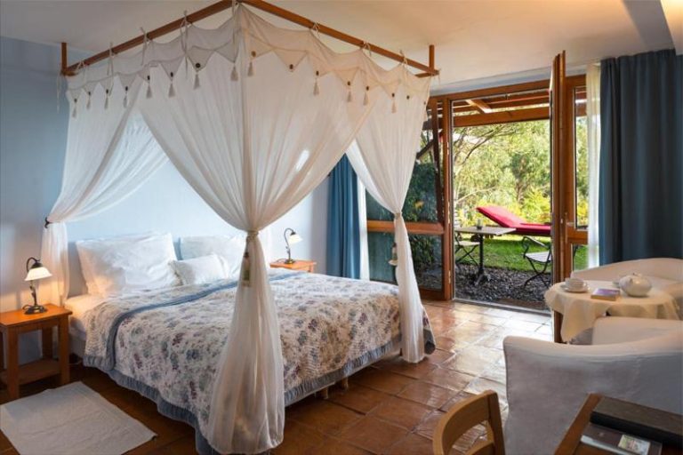 Habitación con cama de dosel y terraza con jardín en Hotel Atrio, decoración romántica y elegante
