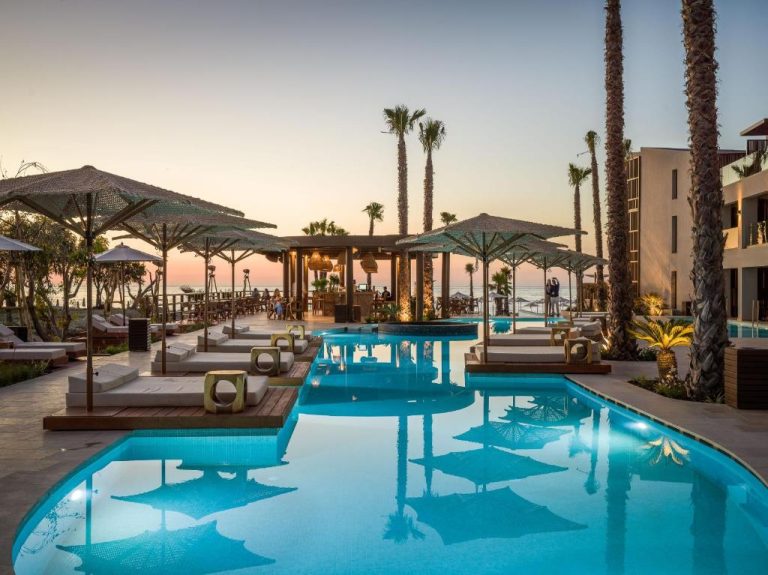 Piscina exterior con tumbonas y palmeras al atardecer en Nalu Resort & SPA Adults Only