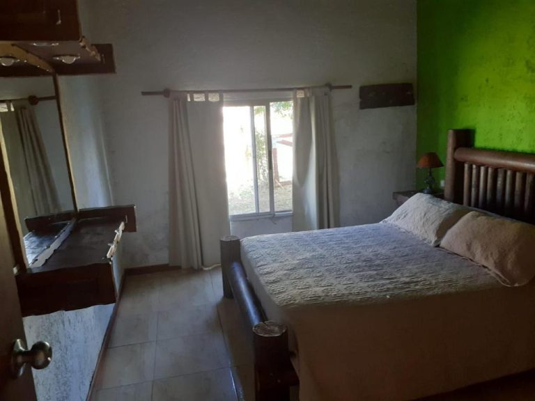 Habitación doble con cama de madera y pared verde en Complejo La Posta del Hum