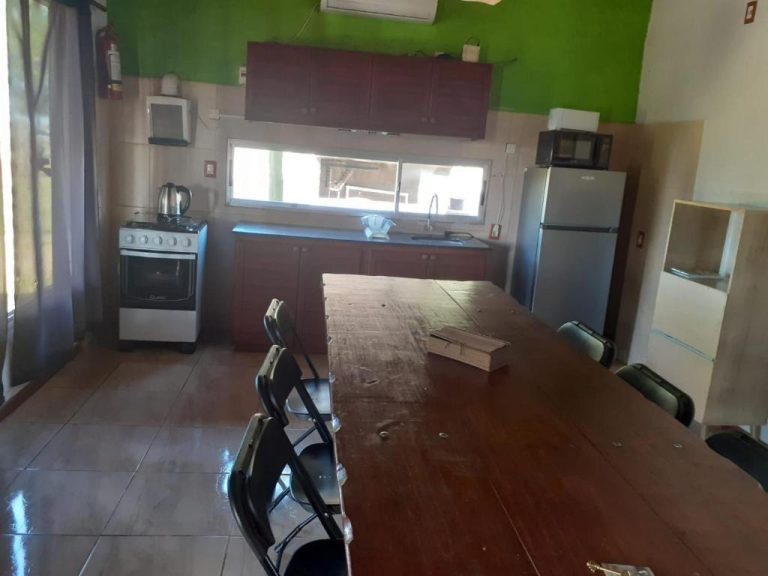 Cocina equipada con comedor, heladera, microondas y cocina a gas en Complejo La Posta del Hum