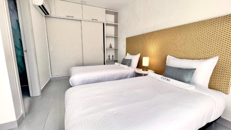 Habitación twin con dos camas y cabecero de ratán en Azure Apartahotel