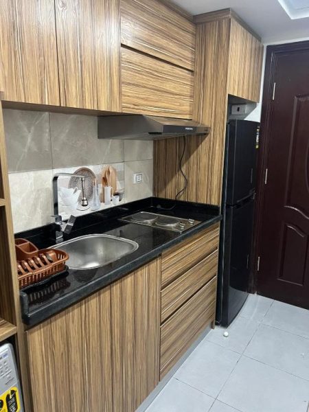 Cocina moderna equipada con armarios de madera y encimera negra en Scandic Resort Hurghada