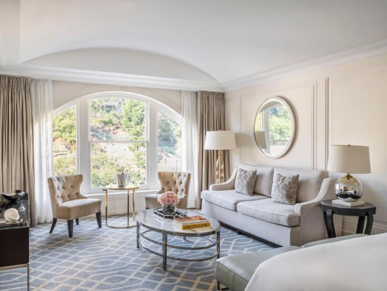 Elegante salón de suite de lujo con sofá, ventanal arqueado y decoración clásica en The Langham Sydney