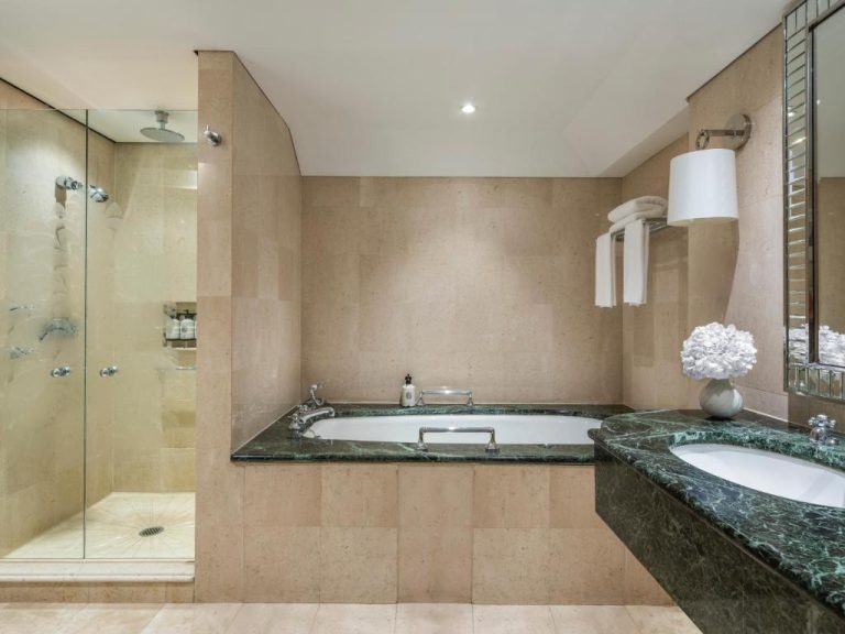 Baño de lujo con bañera empotrada y ducha independiente de mármol verde en The Langham Sydney