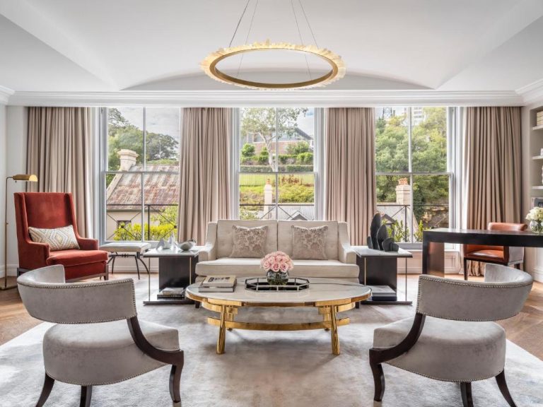 Elegante salón de suite de lujo con sofá, sillones y mesa dorada en The Langham Sydney