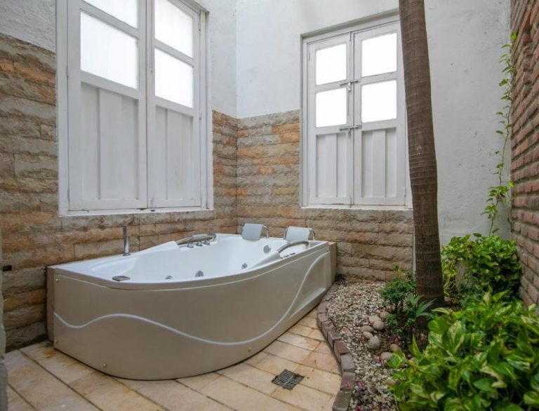 Jacuzzi exterior con jardín y paredes de piedra en el Hotel Boutique Don Pepe
