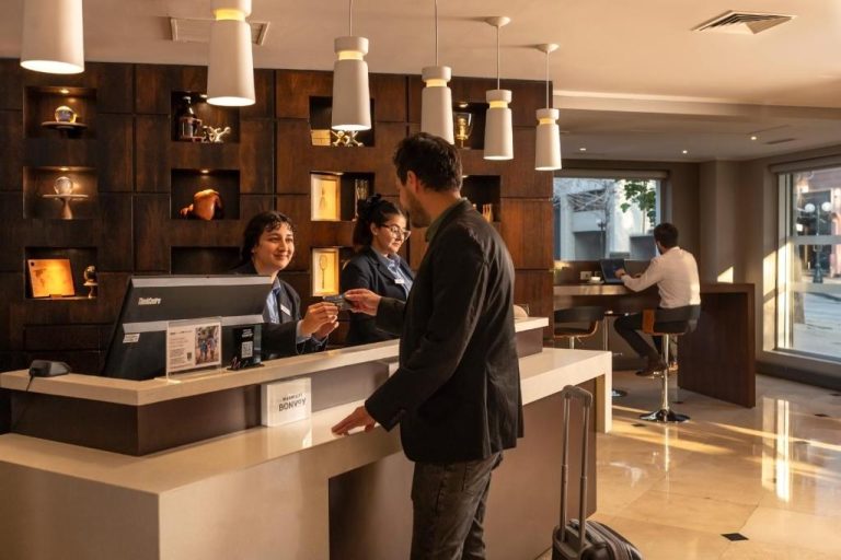Recepción y check-in del Four Points by Sheraton Santiago con personal atendiendo a huésped con maleta