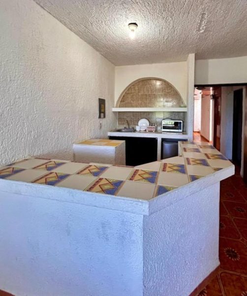 Cocina equipada con barra de talavera y microondas en Íkaro Suites Cancún