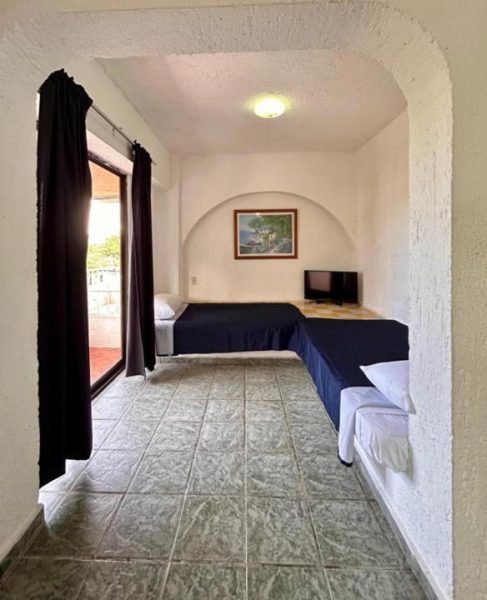 Habitación triple con camas individuales, televisión y terraza en Íkaro Suites Cancún