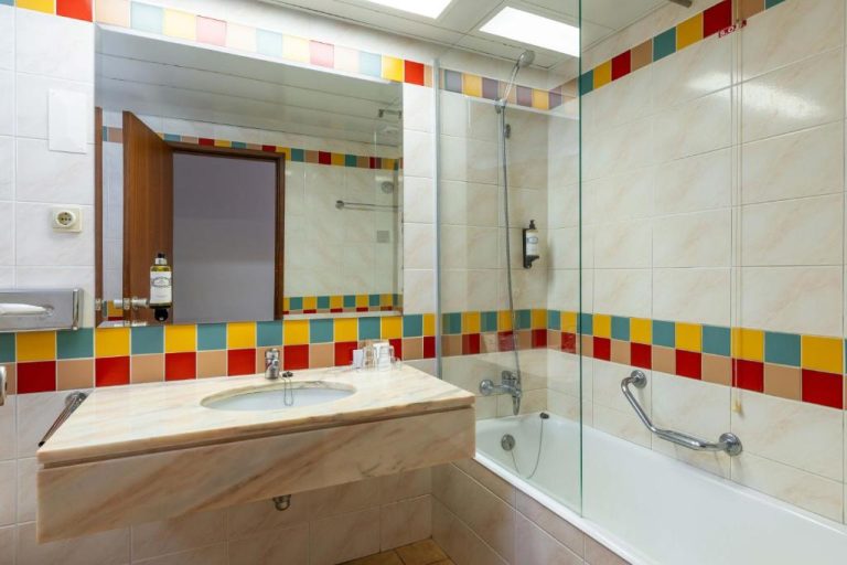 Baño completo con bañera, ducha y lavabo de mármol en el Pestana Ocean Bay Resort