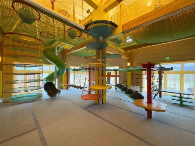 Zona de juegos infantil interior con toboganes y redes de escalada en Hot Springs Medical and SPA