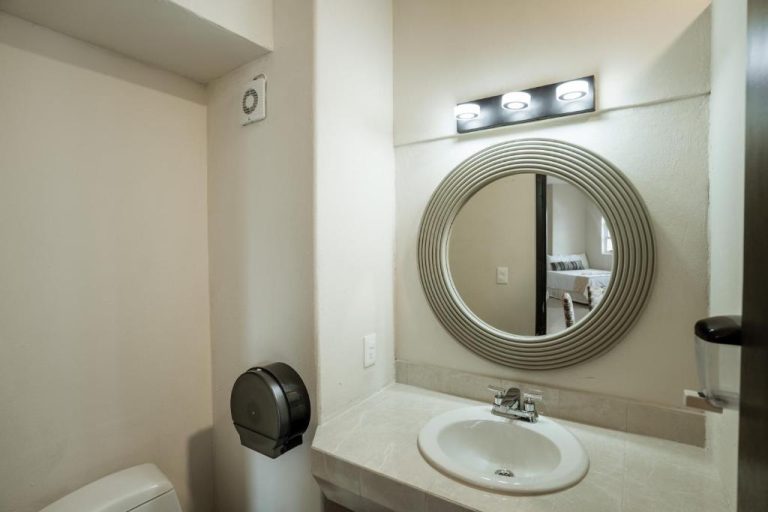 Baño moderno con lavabo empotrado y espejo redondo decorativo en el Gran Sahara