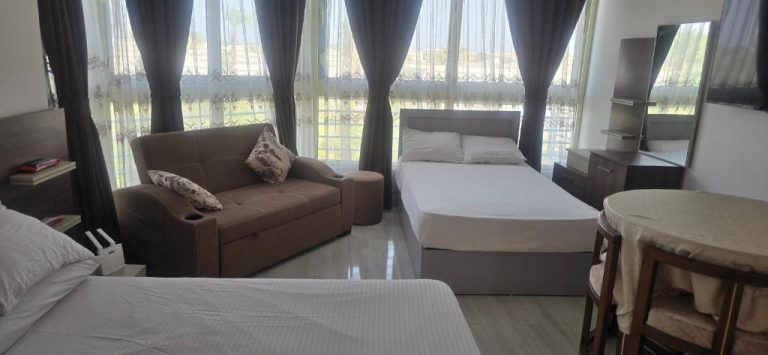 Habitación suite con cama doble, sofá y ampias ventanas en Hotel Mirage Bay con vista exterior