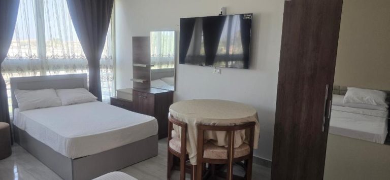 Habitación doble con camas, mesa, televisor y ventanal en Hotel Mirage Bay
