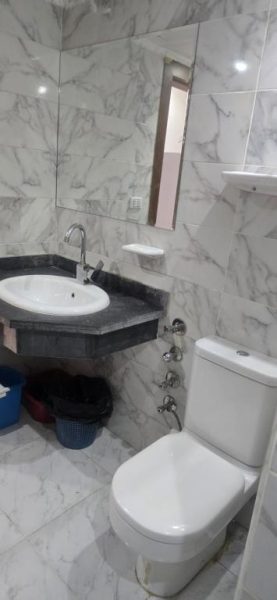 Baño moderno con revestimiento de mármol blanco, lavabo y sanitario en Hotel Mirage Bay