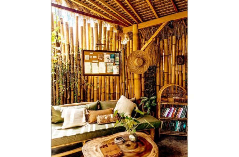Sala de estar con paredes de bambú, sofá con cojines y mesa de madera natural en Hotel Selvática