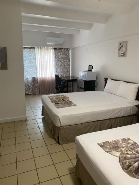 Habitación twin con dos camas dobles, escritorio y aire acondicionado en Pineapple Court Hotel