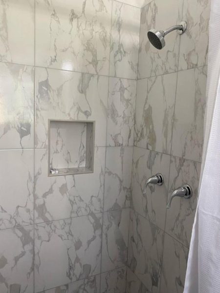 Ducha con azulejos efecto mármol y nicho empotrado en el baño del Pineapple Court Hotel