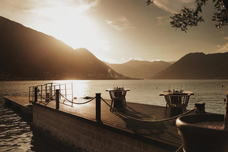 Terraza sobre el lago con mesas al atardecer y vistas a las montañas en HUMA Kotor Bay Hotel
