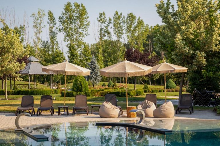 Piscina exterior con tumbonas y sombrillas en el Boutique Complex Trakiets rodeada de jardines