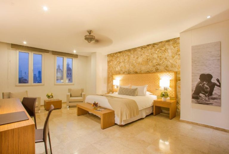 Suite de lujo con cama king size y pared de piedra dorada en Movich Hotel Cartagena de Indias
