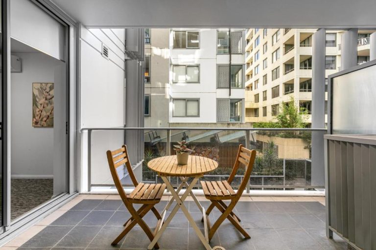 Terraza con mesa y sillas de madera en AAN Apartments North Sydney con vistas al edificio
