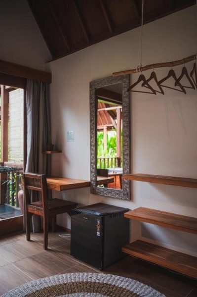 Habitación rústica del Hotel Twiny's con escritorio de madera, espejo decorativo y perchero de bambú