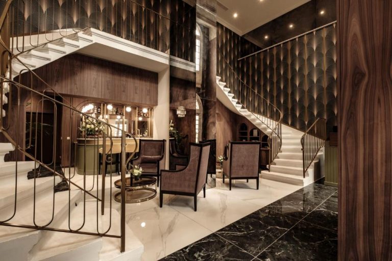 Elegante lobby con escalera Art Déco y zona lounge del hotel 1926 Les Bains Private Spa Suites