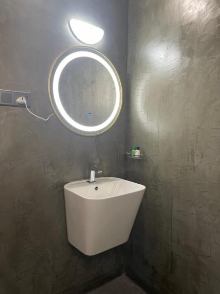 Baño moderno con lavabo suspendido y espejo circular con luz LED en Airport Colombo Pocket Paradise