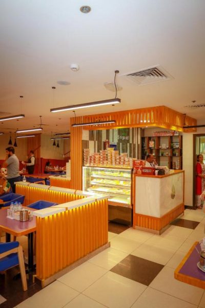 Restaurante del Doha Dynasty Hotel con mostrador de postres y zona de comedor con decoración en naranja