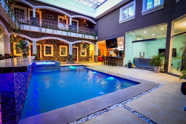 Piscina interior iluminada con jacuzzi y bar del Hotel Bugambilias rodeada de balcones y vegetación