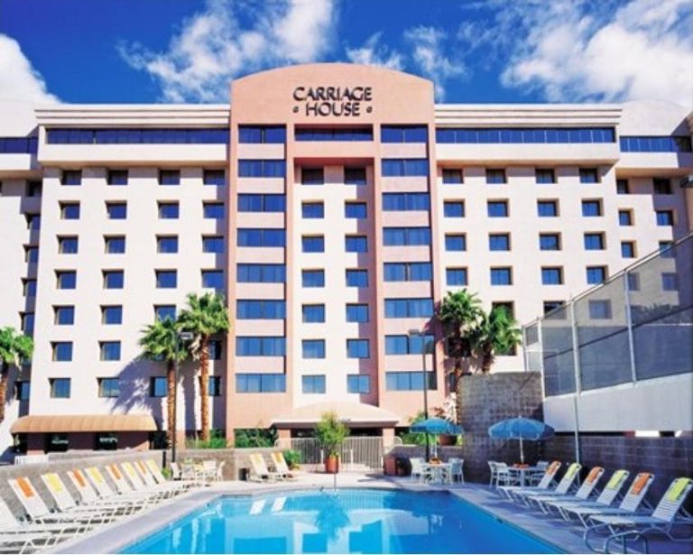 Piscina exterior con tumbonas y palmeras del hotel The Carriage House en Las Vegas