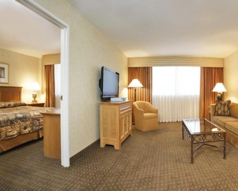 Suite con salón y dormitorio separado en The Carriage House, con sofá, TV y amplia zona de estar