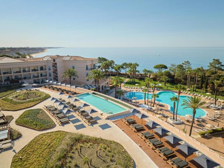 Piscinas exteriores con tumbonas y vistas al mar del hotel PortoBay Blue Ocean en el Algarve