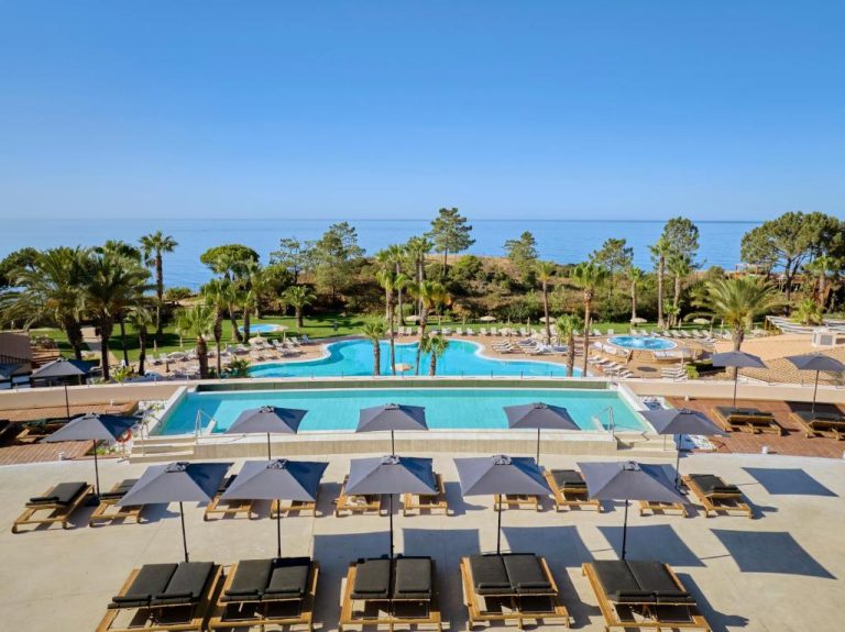 Piscinas exteriores con tumbonas y palmeras del PortoBay Blue Ocean con vistas al mar