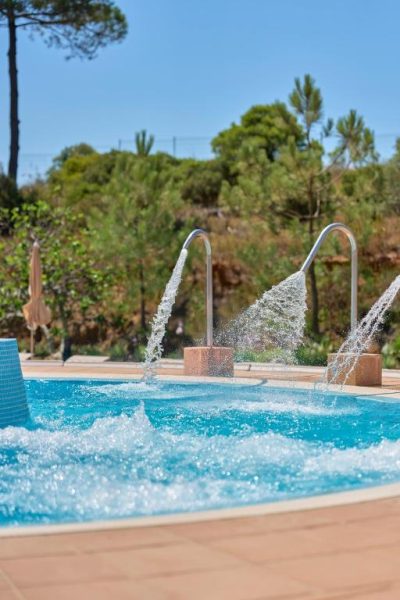 Piscina exterior con chorros de hidroterapia del PortoBay Blue Ocean rodeada de vegetación