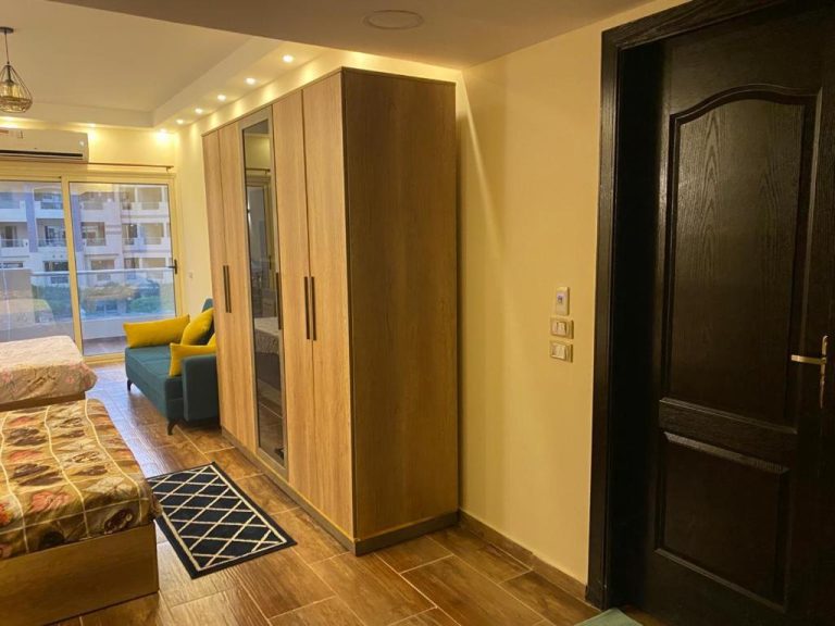 Habitación con amplio armario de madera y sofá azul en el complejo residencial Florenza