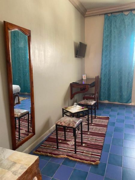 Habitación del Hotel Matmata con espejo de cuerpo entero, taburetes y televisión en pared