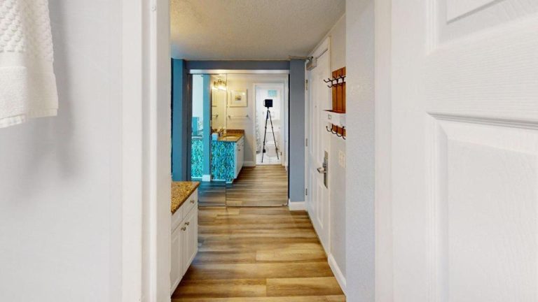 Pasillo con suelo de madera y baño con decoración azul en Island Inn Beach Resort