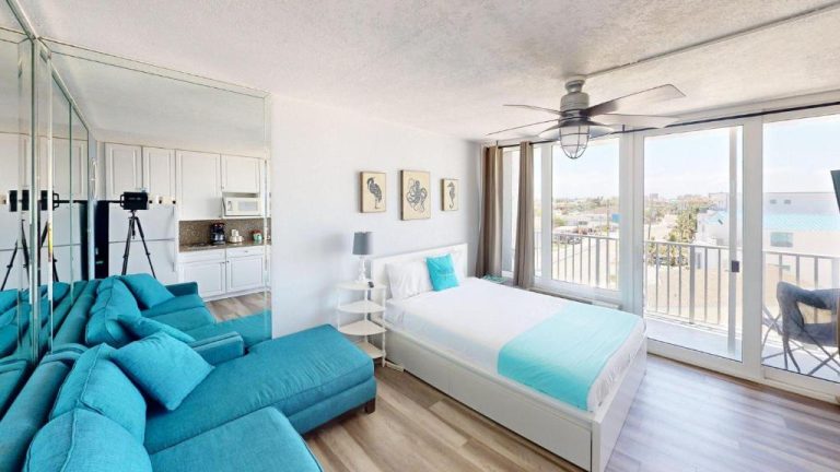 Habitación con sofá azul, cama doble y balcón con vistas en Island Inn Beach Resort