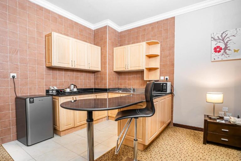 Cocina equipada con microondas, nevera y barra de desayuno en Kingsgate Hotel Doha by Millennium Hotels