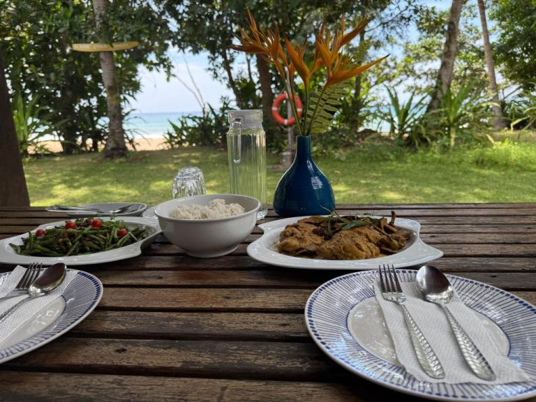 Mesa con platos de comida tropical y vistas a la playa en el restaurante del Kiao Beach Hotel