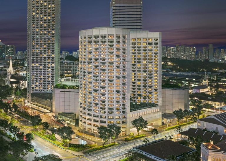 Vista aérea nocturna del Fairmont Singapore con sus torres iluminadas en el centro de Singapur